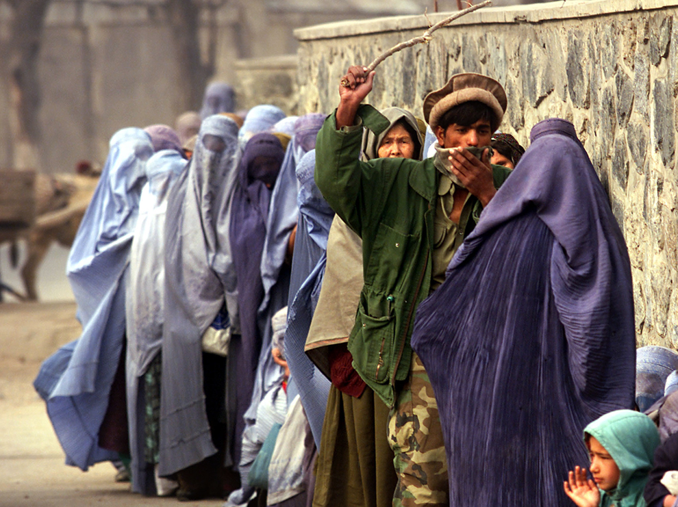 / 现实中的阿富汗女性：2001年，一名阿富汗士兵用木棍在等待人道主义援助的妇女中“维持秩序” (Damir Sagolj/Reuters) /