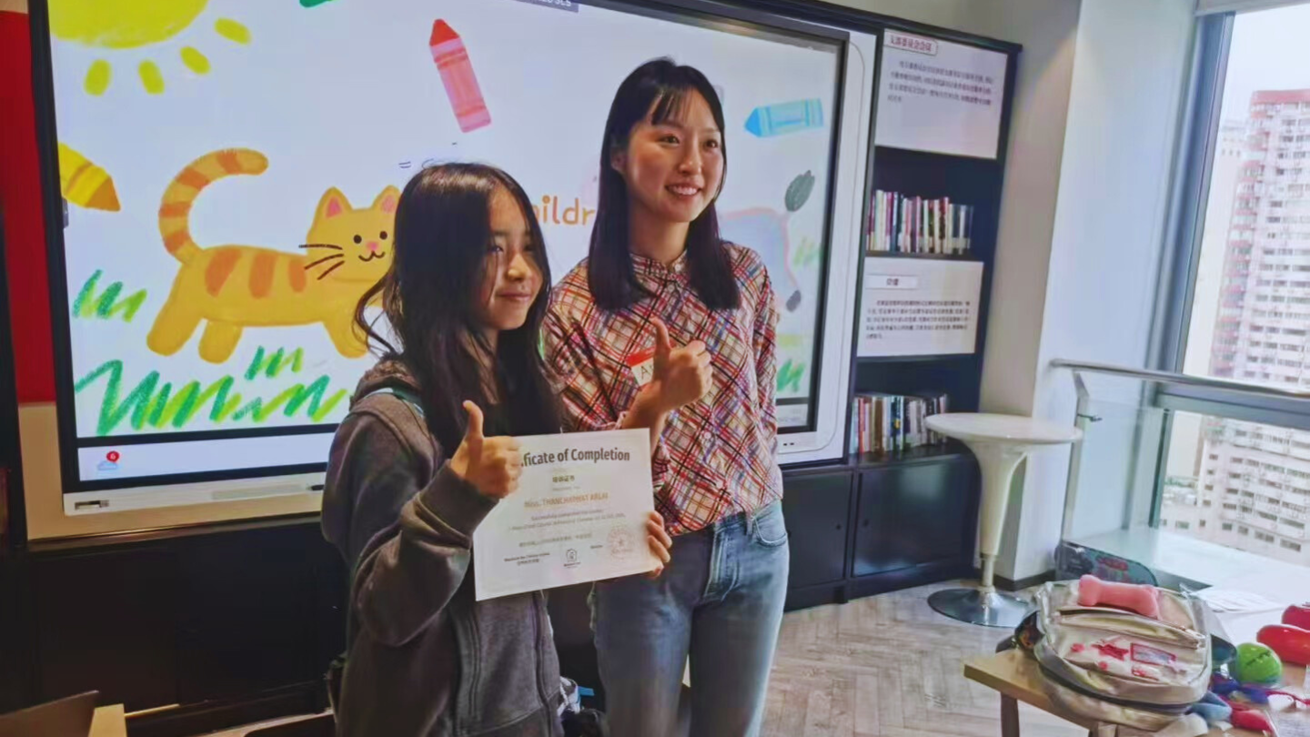 A student hold the certificate proudly with her teacher in Mandarin inn