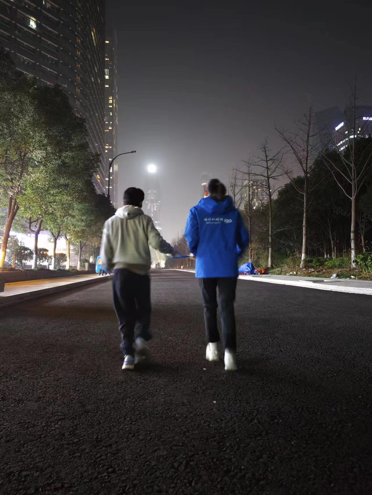 月丽和陪跑伙伴牵起陪跑绳在夜晚的灯光下畅快奔跑 Yue Li and her guider run with the rope freely under the night light