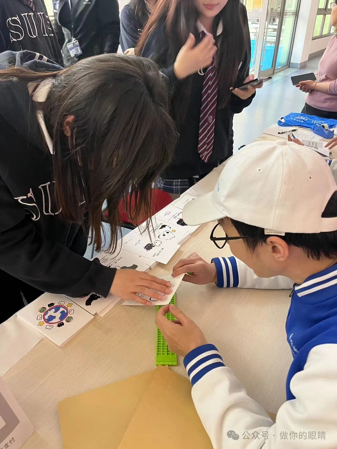 蓝睛灵在学校开展多种体验活动，同学们在触摸盲文 Lanjingling conducting various experiential activities at schools,Students touching Braille